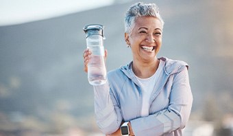Woman smiling with water bottle on hike outside