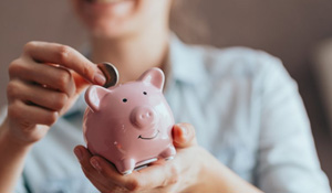 Woman inserting a coin into her piggy bank