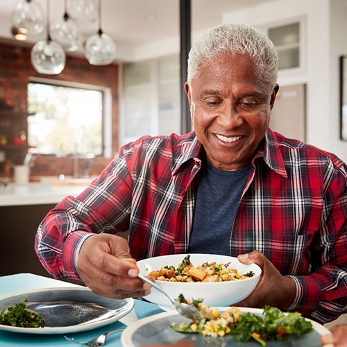 Senior man smiling while plating meal at home